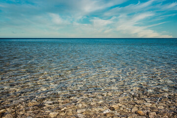 shallow pebble beach water with blue sky