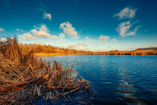 Landscape photography on the wide-angle lense, river at the morning in the fall season.Blue and beautiful water,reclections on water.Clouds in the blue sky, trees on the beach , sunny morning.Branches