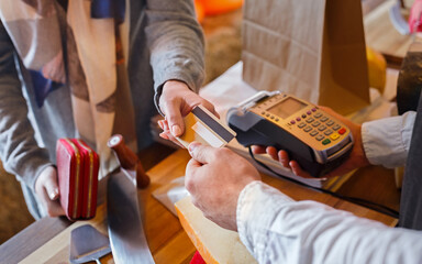 Credit card payment service. Customer paying for order of cheese in grocery shop.