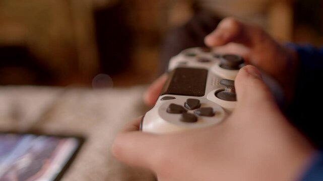 A person is actively engaged in gaming using a controller, while a tablet sits in the background - Powered by Adobe