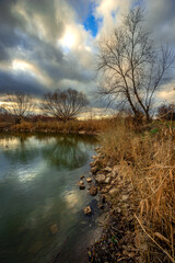 Beautiful landscape with lake and big and smooth clouds in the sky , autumn season, water and trees . Reflections on the water , stormy clouds in the sky . Photography in the forest iwith lake .