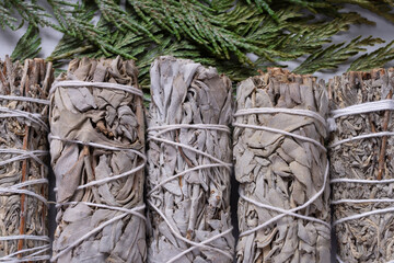 A top view image of several white sage smudge sticks on a cedar bow background.