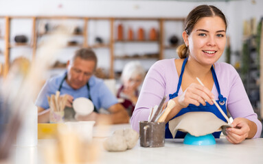 hobby of young brown-eyed brunette - classes in workshop of experienced potter