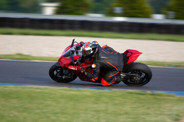 Fototapeta premium Motorcycle rider on a red sport bike riding fast through a corner 