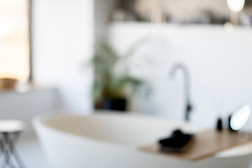 A spacious and bright modern bathroom showcases a freestanding tub, a stylish sink, and plants providing a touch of nature. The atmosphere is serene, perfect for relaxation.