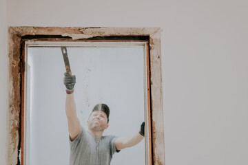 A man working with a crowbar in a doorway.