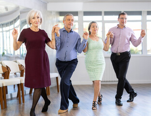 Group men and women dancing folk dance in row in studio