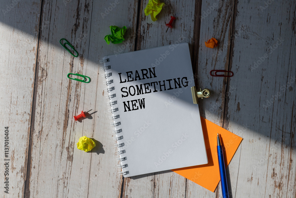 Poster learn something new - words in white notebook on white background with pencil.