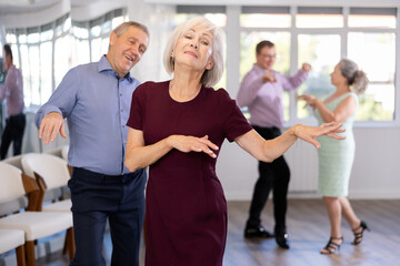 Fototapeta premium Couple of elderly man and elderly woman dancing twist in studio