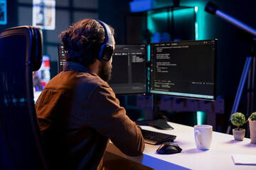 Man listening music while doing software quality assurance, reading source code on computer screen....