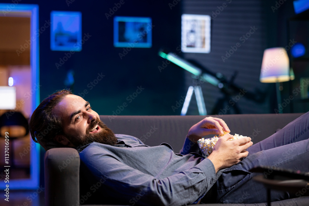Poster amused person lounged on couch using tv to binge comedy series on subscription based streaming servi