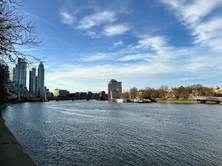 Nine Elms, London, United Kingdom - 24th December 2024 - Winter view along River Thames showing modern residential towers, moored boats and Vauxhall Bridge under blue skies