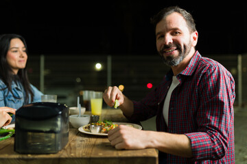 Cheerful guy garnishing his tacos with lime during a fun evening with friends at a mexican taco eatery