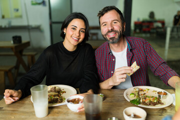 Happy hispanic couple savoring authentic flavors while enjoying tacos and drinks at a traditional mexican taqueria
