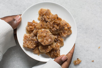 Overhead view of nigerian coconut candy on a white plate, top view of candied coconuts discs, flatlay of bukayo candy or coconut drops