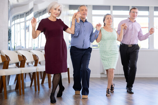 Group men and women dancing folk dance in row in studio