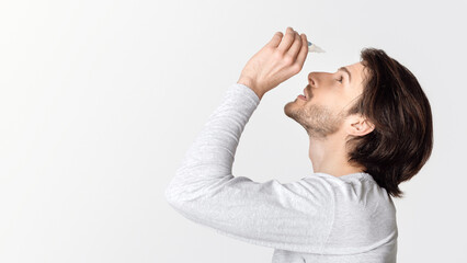 Dry and pain in eyes. Guy dripping eye drops, profile