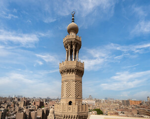Obraz premium The impressive minaret of Al-Muayyad Mosque, against a backdrop of the bustling city of Cairo, highlighting its historical significance and architectural beauty. 