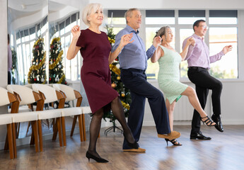 Group of men and women dancing traditional folk dance in studio..