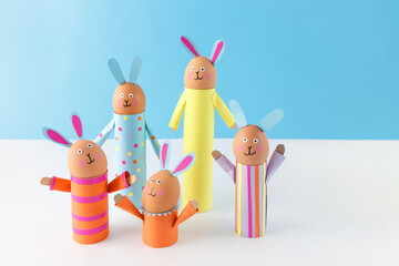 Handmade Easter bunny crafts using colored paper and eggs on a blue background. Studio photography for design and print. Easter celebration and DIY craft concept
