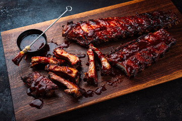 Barbecue spareribs St Louis cut with hot rub and BBQ sauce served as close-up on a wooden design...
