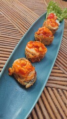 Fried Sushi Rolls with Sauce and Fresh Vegetables at bamboo table
