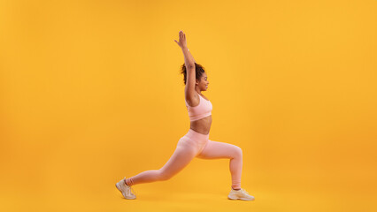 A young woman is executing a yoga pose in a bright studio filled with a cheerful yellow backdrop....