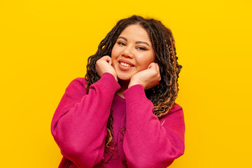 plump african american woman with dreadlocks smiling on yellow isolated background, big plus size girl with pigtails looking at camera