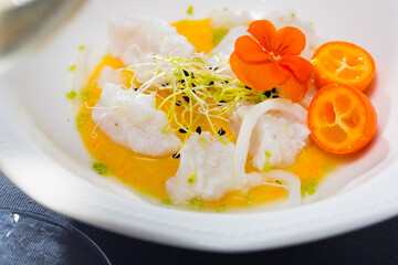 Close up of tasty seafood ceviche from horse-mackerel with spicy avocado sauce, greens and cumquat