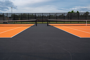 Tennis court net and post on orange and black tennis court - pickleball court with white baseline...