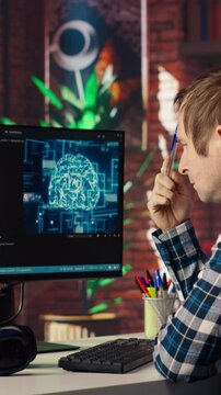 AI software developer at computer waiting for code to finish compiling, rubbing forehead with pen, feeling bored. Impatient man waits for artificial intelligence scripts to finish compiling, camera B