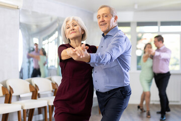 Active elderly people attend dance lessons for amateurs and learn to dance tango in their free time