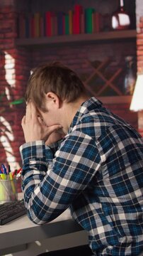 Coder at workstation programming on PC, writing lines of code, using development tools, feeling stressed. Man in home office having deadline, stressed to finish debugging software, camera A