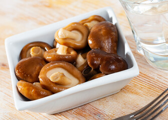 Delicious homemade pickled shiitake mushrooms garnished with onion on white plate