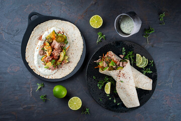 Italian style wrap piada wheat tortilla with tuna fish, vegetable and avocado served as top view on a Nordic design plate