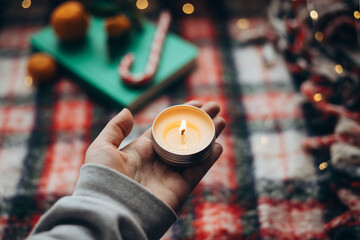 Candle held up against a festive holiday background