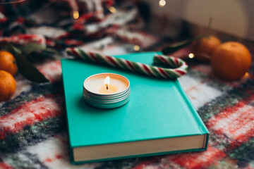 Holiday book and candle on festive blanket