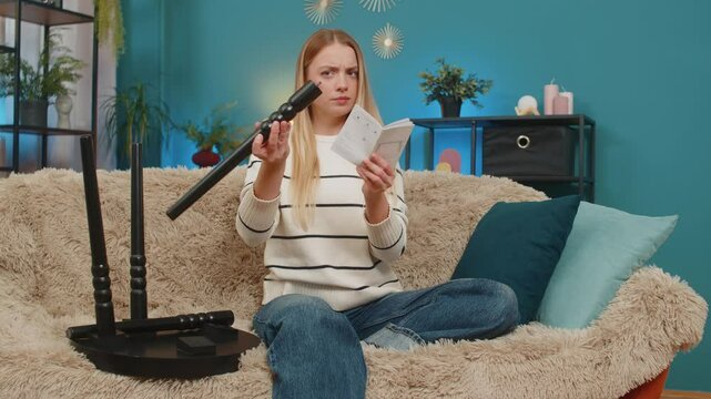 Caucasian woman girl tries to assemble small table from printed instructions sitting at home on sofa. Looks confused, worried, slightly frustrated, uncertain, holding a paper diagram, feeling unsure