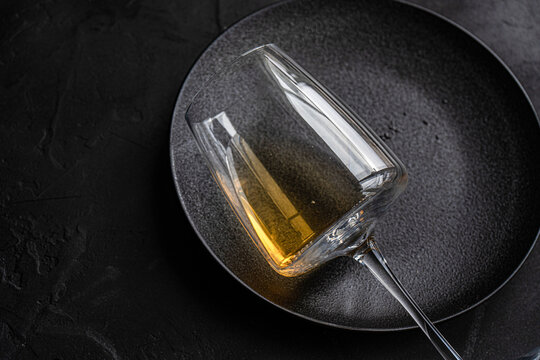 Elegant dry white wine in a glass on a textured black plate