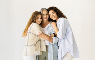 Happy caucasian senior, mature and teen women hugging, enjoy love on white wall background....