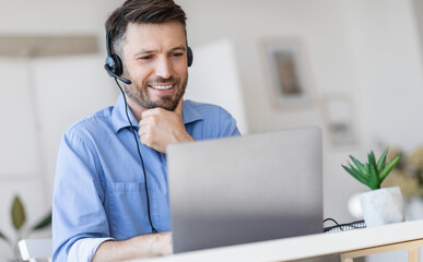 Hotline Support Service. Handsome male call center operator in headset working with laptop in...