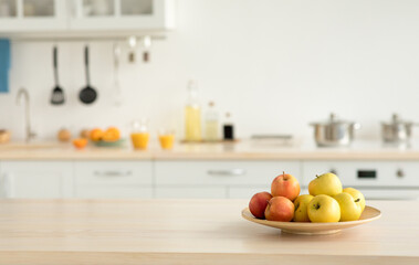 Cozy home kitchen design and comfortable style, ad for rent. Plate with apples on table, bottles of sauces and utensils, orange juice in glasses and fruits, light walls and white furniture, copy space