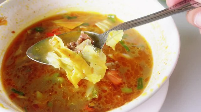 "Tongseng Kambing" (lamb tongseng) with vegetables in a white bowl, on a white background 