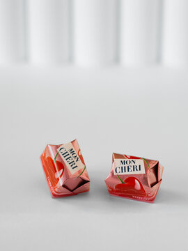 Mon Cheri pralines in packaging on white background, chocolates with liqueur and cherry by Ferrero, close-up, minimalist style, empty space for text, December 15, 2024, San Stino di Livenza, Italy.