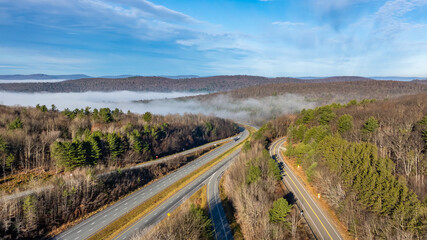 Nearly empty highway on a sunny day descending into thick fog, cloud cover, creating a mysterious...