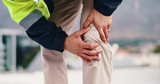 Person, hands or architect with knee pain for accident, muscle tension or inflammation on rooftop site. Closeup, builder or civil engineer with sore leg, joint or sprain for arthritis or fibromyalgia