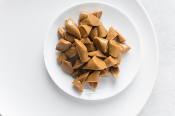 Overhead view of iloka candy on a white plate, top view of cooked condensed milk candy, Nigerian iloka candy on a white background