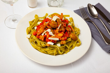 Spinach pasta with olives, cheese and gravy closeup