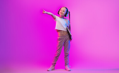 A preteen girl stands confidently against a pink neon backdrop, showcasing her stylish outfit. She...