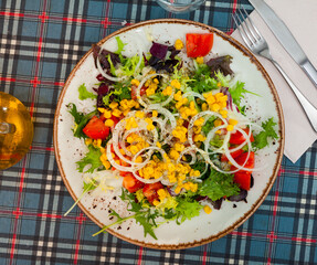 Light vegetable salad made from fresh chopped tomatoes, onions, lettuce leaves and corn